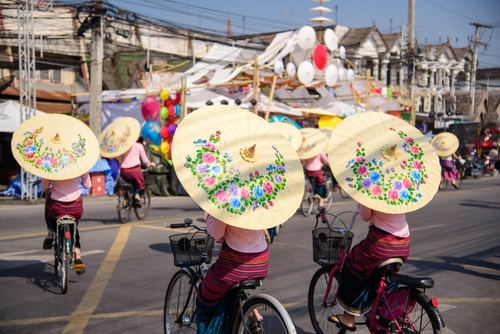 Women biking with floral umbrellas | Travel with Joy