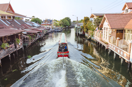 The long tail boat cruising through WATKHUHASAWAN TEMPLES at Bangkok yai canal or Khlong Bang Luang Tourist Attraction with waterfront house from local around water, Bangkok, Thailand