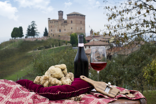 Still Life of White Truffles from Piedmont, truffles cuts and bottle with glass of red wine, with a view of the vineyards and the castle of Grinzane Cavour