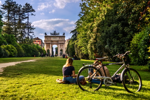 People resting and walking in the Sempione Park near Arco della Pace known as Arch of Peace, one of the most famous landmarks, in the historic center of the city of Milan, Lombardy, Italy
