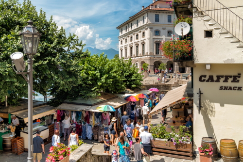 Tourists visiting outdoor market in the historic center of Bella Island, one of the Borromean Islands of lake Maggiore. Stresa, Lake Maggiore, Lombardy, Italy