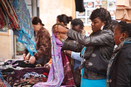 French women of African ethnicity browse a market stall in Quartier Belleville in Paris, France
