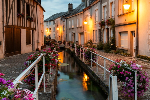 Evening in Beaugency with old houses and lots of flowers (Pelargonium) at a fence along a creek, Loire, France