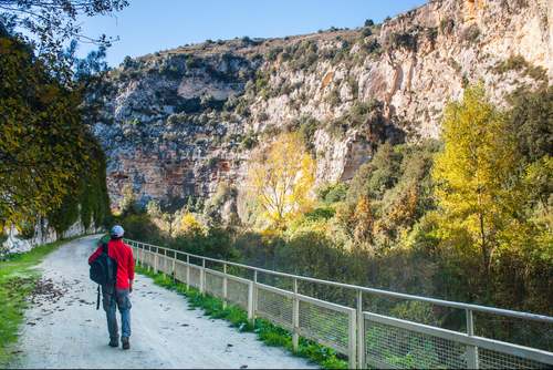 Hiker walking along the trails of the Anapo valley, by the rocky necropolis of Pantalica in Sicily, Italy
