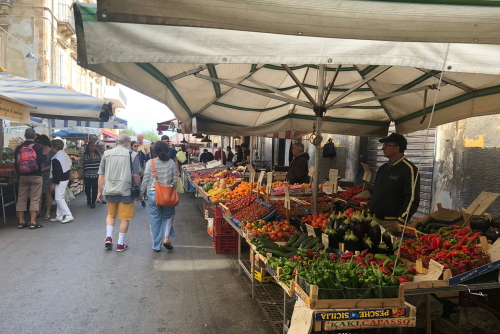 People walking through the fresh fruit and vegetables market on the island of Ortygia, Syracuse, Sicily, Italy