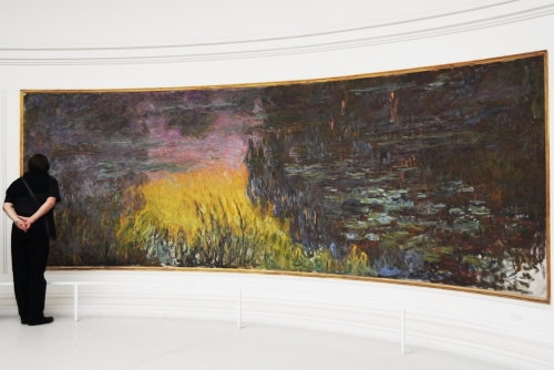 Visitors admire giant paintings by impressionist painter Monet Water Lilies Nimphaea at Paris Orangerie Museum (Musee De L'orangerie), Paris, France