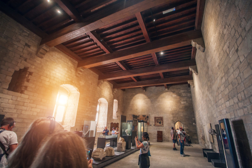 Dramatic lighting with people visiting the interior halls and exhibitions at the Palace of the Popes in the city of Avignon, Provence, France