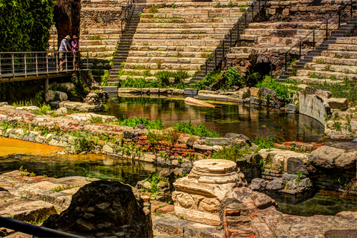 A couple overlooking at the pool created at the bottom of the open-air Roman Theatre, part of the Parco archeologico Greco-Romano di Catania, Sicily, Italy