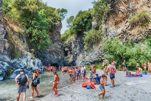 People enjoying a cold water bath at the Alcantara River Park, an impressive system of gorges and ravines near Taormina, Sicily, Italy