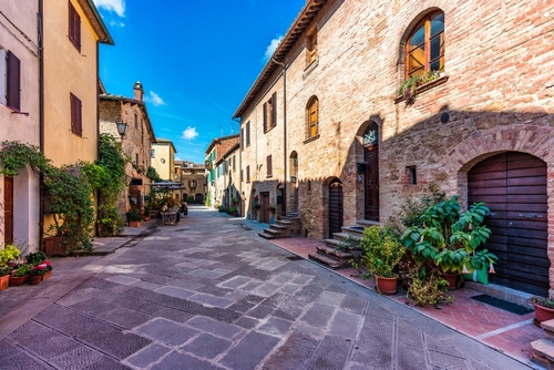 Cozy street decorated with colorful flowers in the charming town of Pienza in Val d'Orcia, Tuscany, Italy