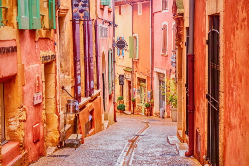A narrow street in the beautiful French village of Roussillon, where the buildings are made with colorful, locally mined ochre, Provence, France