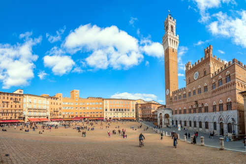 Tourists enjoy Piazza del Campo square in Siena, Tuscany, Italy. The historic centre of Siena has been declared by UNESCO a World Heritage Site