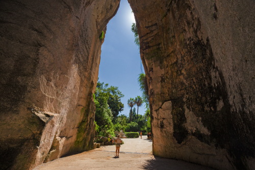 Some tourists at the exit of the excavated cave, called Orecchio di Dioniso (Ear of Dionysius), near the Greek theater of Syracuse, Sicily, Italy