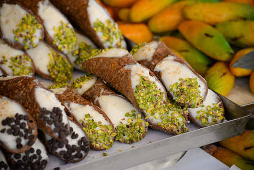 Sweet homemade cannoli stuffed with ricotta cheese cream and pistachial Sicilian dessert at market in Italy