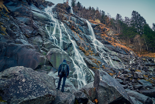 Young man admiring Beautiful Nardis waterfalls in Val di Genova, Adamello-Brenta Natural Park in the northern Italy