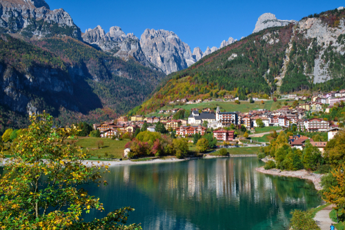 Aerial view of Lake Molveno, Trentino Alto Adige, northern Italy in the background the city of Molveno, Alps, blue sky, Autumn season