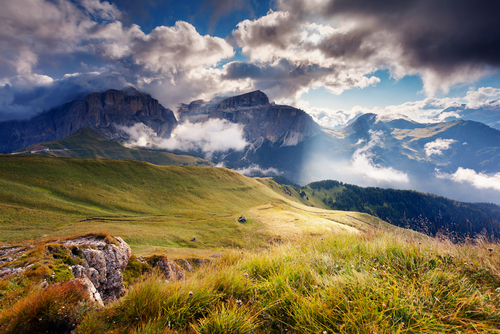 Great view of the foggy Val di Fassa valley with pass Sella. National Park. Dolomites (Dolomiti), South Tyrol, Canazei, Campitello, Mazzin. Italy. Dramatic scene