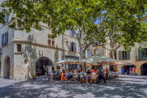 People sit outside at lunch at the start of summer in the city of Uzes, Provence, France