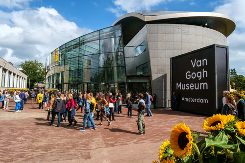 Crowd in front of the new wing of the Van Gogh Museum with sunflowers in the foreground, Amsterdam, The Netherlands