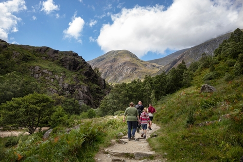 A family walks on the Ben Nevis mountain path leading to Steall waterfall in Scotland, UK