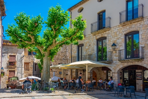 People sitting in a cafe in a Medieval street in the Spanish town of Besalu, Catalonia, Spain