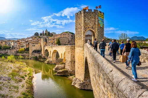 Tourists entering via the bridge over the river Fluvia in the medieval village de Besalú, Catalonia, Spain