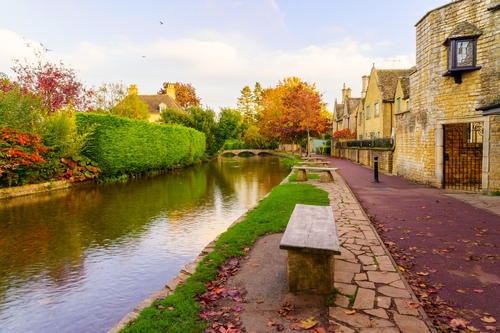 Sunset view of typical houses, and the river Windrush, in the village Bourton-on-the-Water, the Cotswolds region, Gloucestershire, England, UK