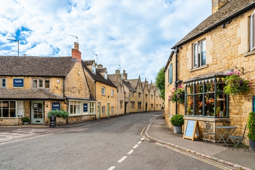Shops, restaurants and traditional stone houses on Victoria Street, in the village Bourton-on-the-Water, the Cotswolds region, Gloucestershire, England, UK