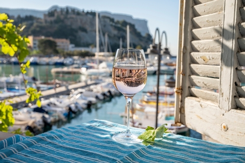 Rose Provencal wine in glass served on outdoor terrace with view on old fisherman's harbour with colourful boats in Cassis, Provence, France