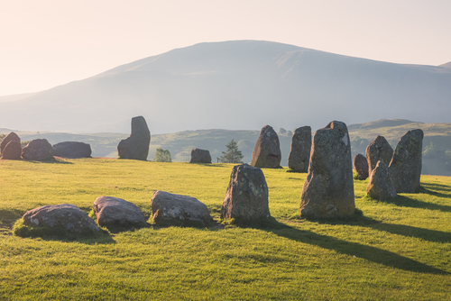 Golden sunrise or sunset light cast across the historic and sacred megalithic site Castlerigg Stone Circle near Keswick, the Lake District National Park, Cumbria, England, UK