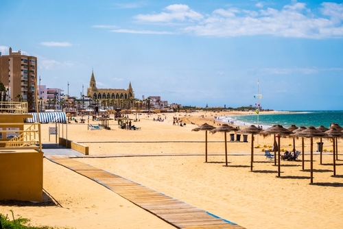 Great view of Chipiona beach in Cadiz Province, Andalusia, Spain, blue sky, white sand, palm trees