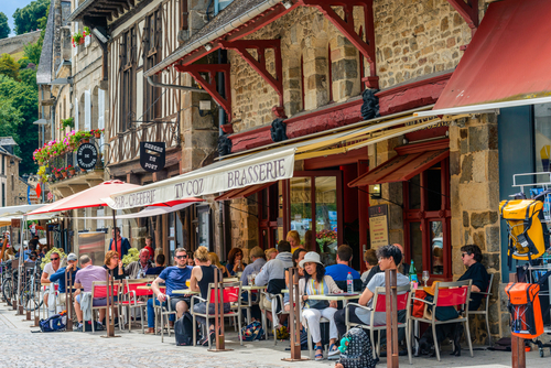 Dinan, Brittany, France. Outside tables in front of a busy creperie and brasserie, Ty Coz, in the Port of Dinan, a lower part of town built alongside the River Rance