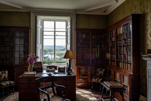 Old library with a desk and vintage lamp in a historical room with bright window in Dunvegan Castle, Isle of Skye, Scotland, United Kingdom