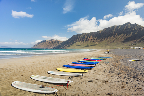 Colorful surfboards on the Famara beach on the Atlantic ocean during a warm Sunny Summer day on Lanzarote island, The Canary Islands, Spain
