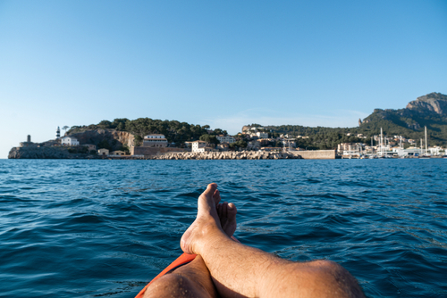 POV shot of a man laying on a kayak while taking a sunbath at Port de Soller, Mallorca island, Balearic Islands, Spain
