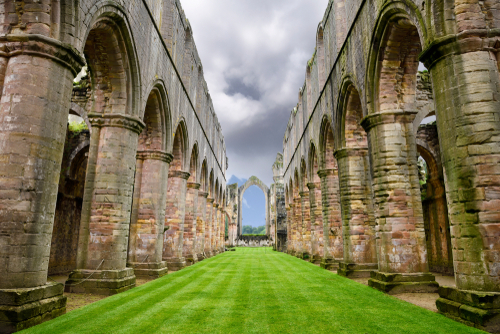 Colorful stone pillars in the nave of Fountains Abbey Cistercian monastery church ruins with green grass Fountains Abbey, Yorkshire Dales National Park, North Yorkshire, England, UK