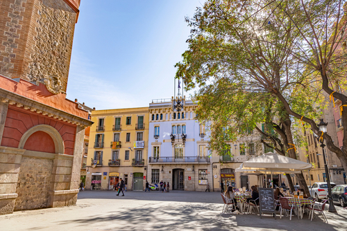 Plaça de la Vila, in Gracia quarter, Part of the bell tower, the Gracia town hall (blue building) and a bar terrace in Barcelona, Catalonia, Spain