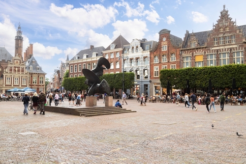 People walking and enjoying the beautiful day at the Historic houses on the main square in the center of Haarlem, Holland