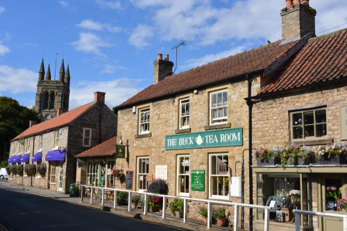 Street scene with row of shops and a The Beck tearoom, with church tower in the background, Helmsley, North Yorkshire, England, United Kingdom