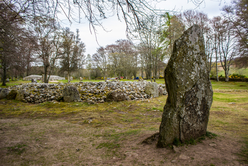 The Prehistoric Burial Cairns of Bulnuaran of Clava, Scotland, United Kingdom. Sheltered in a grove of Beech Trees, with a large standing stone in the foreground