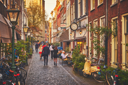 People walking and sitting in cafes in a cozy street in old Leiden during Sunset, The Netherlands