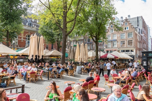 People sitting in restaurants and cafes on the terrace on the popular Leidseplein in Amsterdam, Holland