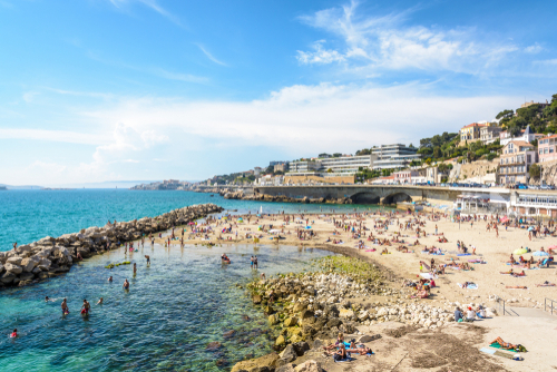 People sunbathing and swimming on the Prophet beach, a very popular family beach located on the Kennedy corniche, on a hot and sunny spring day, Marseille, Provence, France