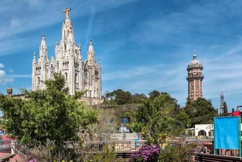 View of Tibidabo Cathedral in Barcelona, Catalonia, Spain. Temple of the Sacred Heart of Jesus at Mount Tibidabo. High tree tree and blue sky with cloud of summer day