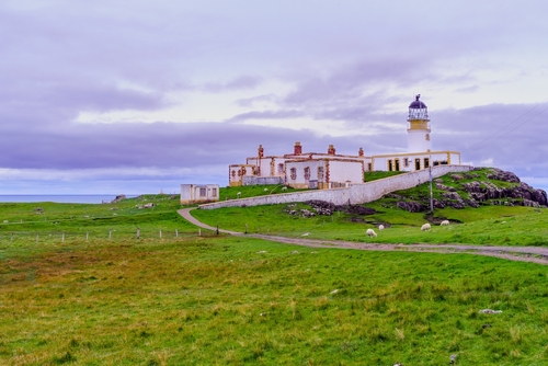 Sunset view of Neist Point Lighthouse, coastal cliffs, and rocks, in the Isle of Skye, Inner Hebrides, Scotland, UK