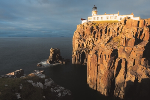 Dramatic golden sunset or sunrise light on the coastal seascape headland peninsula of Neist Point Lighthouse on the Isle of Skye, Scotland, United Kingdom