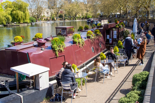 People having a coffee and meeting with friends at a canal boat cafe in Little Venice, on a sunny Sunday morning in London, England, UK