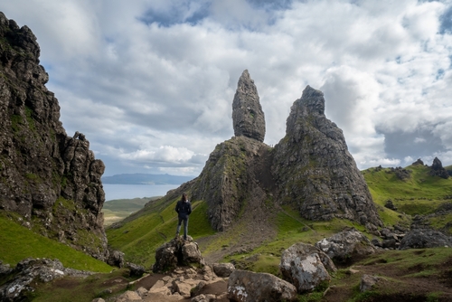 Woman looking at the massive rock formations of the Old Man of Storr, Isle of Skye, Scotland, UK