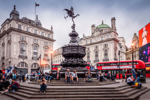 The historic architecture of London, England, United Kingdom at Sunset showcasing Piccadilly Circus with lots of locals and tourists passing by