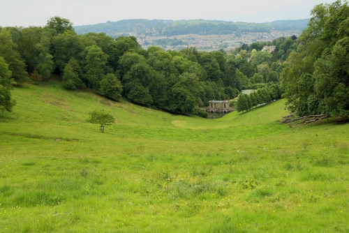 Landscape view of luscious greenery and the 18th century Palladian Bridge in the Prior Park Landscape Garden in Bath, Somerset, England, United Kingdom